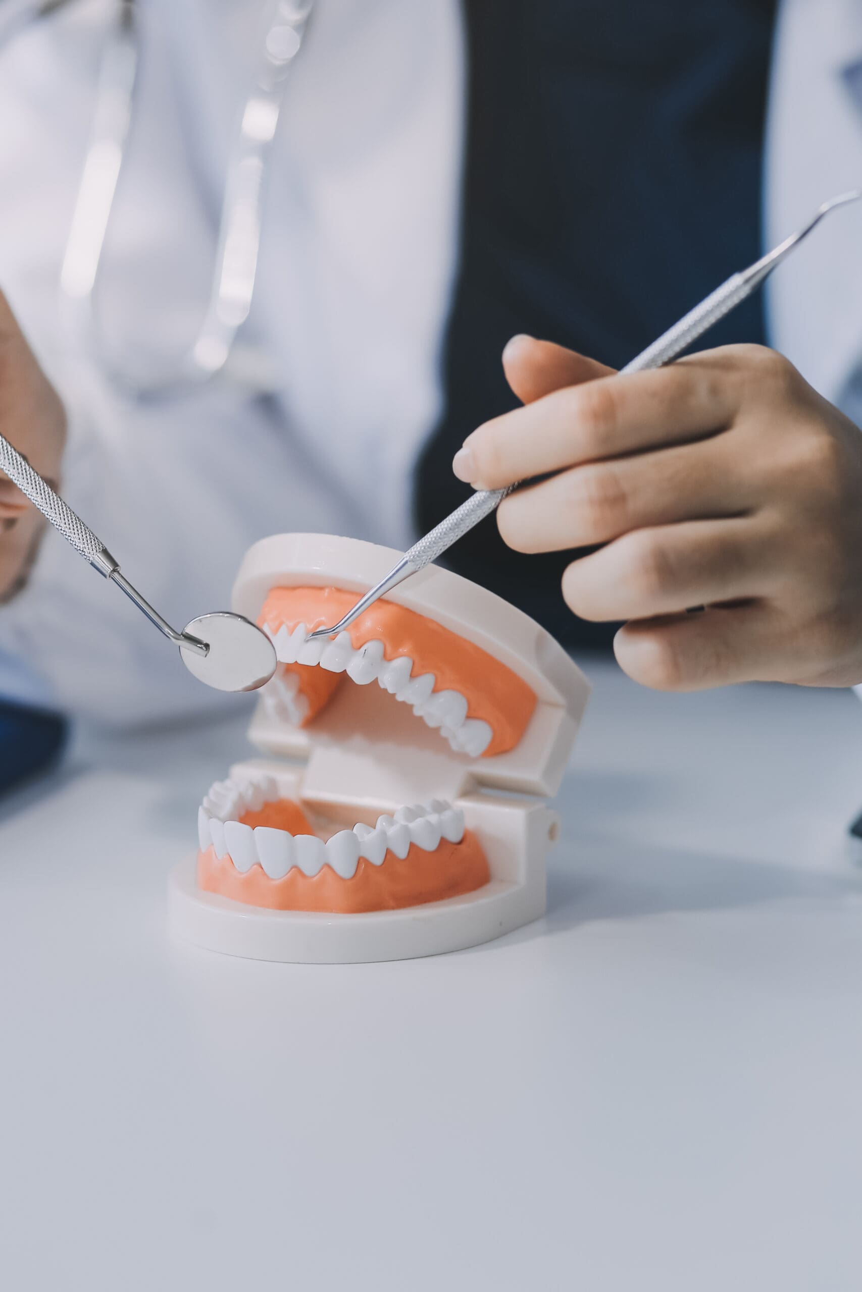 Periodontist demonstrating gum disease and periodontal treatment on a dental model using a mirror and scaler at an Elkhart periodontal office.